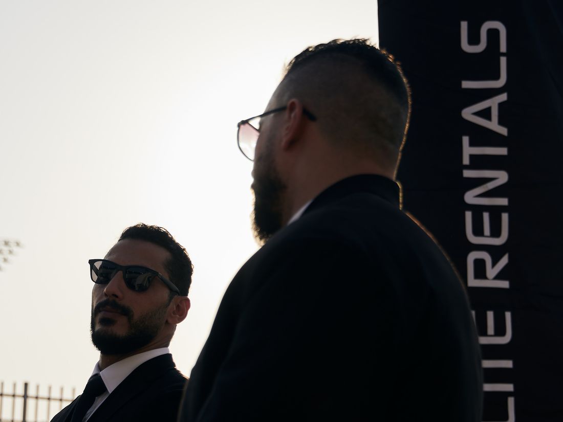 Security detail beside the Elite Rentals flag at dusk